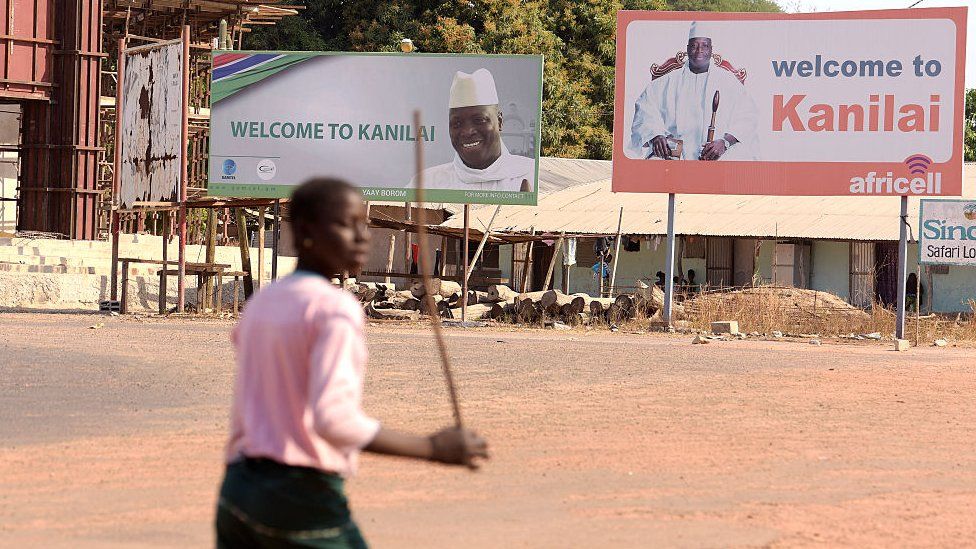 A person walks past boards bearing pictures of Yahya Jammeh in his home town of Kanilai, The Gambia - 22 January 2017