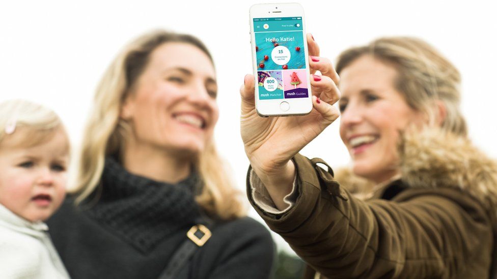 Two mums holding phone with Mush app open