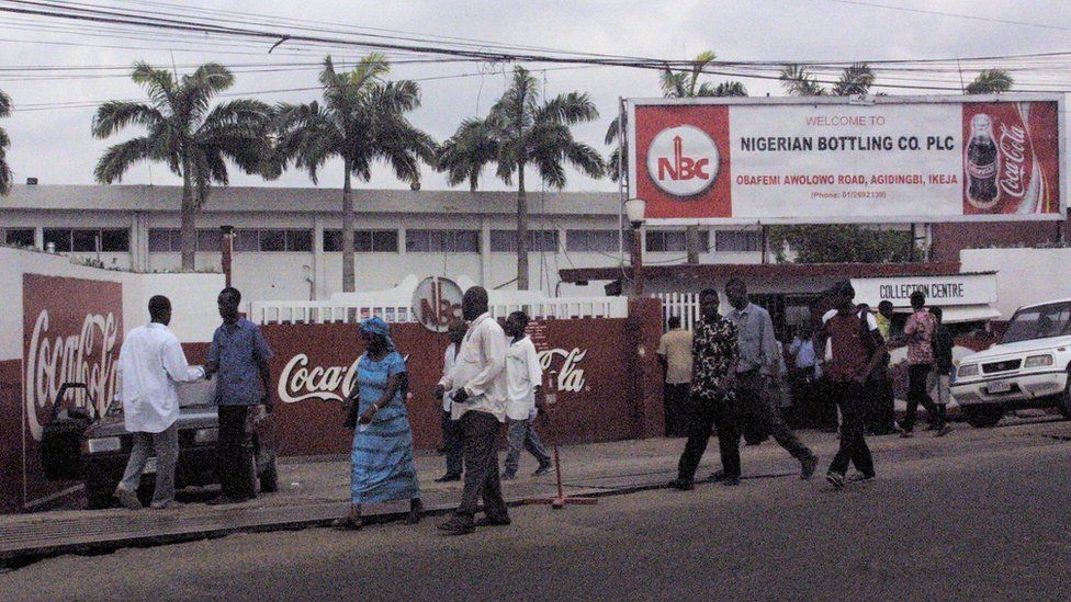 Passers-by walk past the Nigerian Bottling Company in Lagos