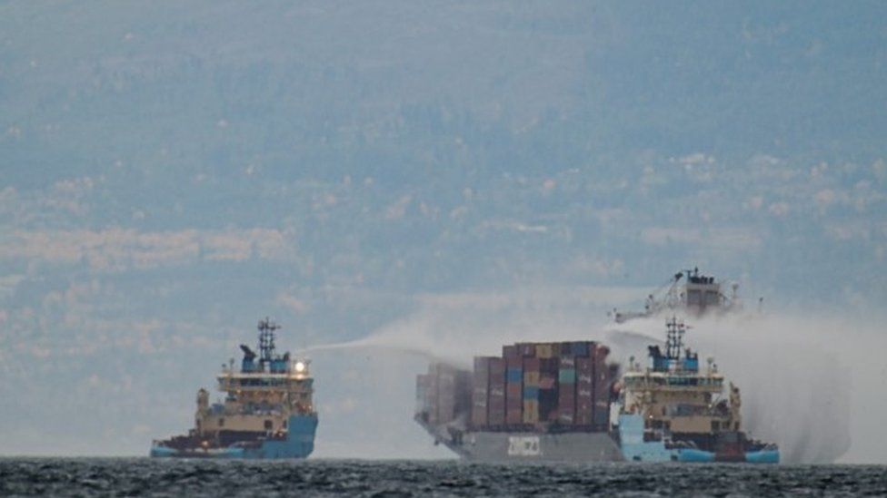 Salvage tug boats spray what appears to be water onto the container ship Zim Kingston after the crew were evacuated due to a fire on board, in Victoria, British Columbia