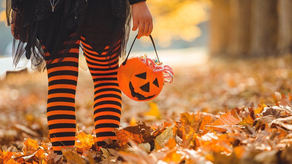 Child in a costume holding a trick-or-treat bucket