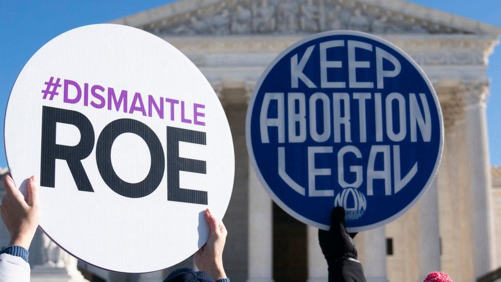 Signs reading "dismantle Roe" and "keep abortion legal"