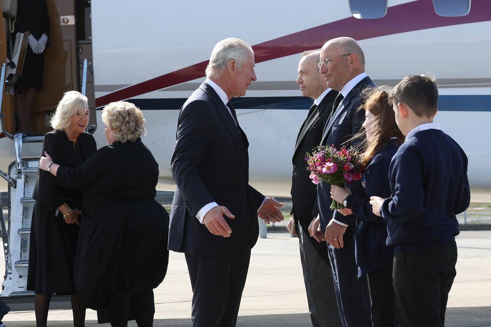 King Charles and Camilla are greeted at Belfast City Airport by Lord Lieutenant of Belfast Fionnuala Jay-O'Boyle, Northern Ireland Secretary Chris Heaton-Harris, airport chief executive Matthew Hall and schoolchildren Ella Smith and Lucas Watt