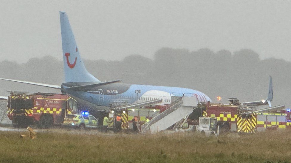 Plane off runway surrounded by emergency vehicles