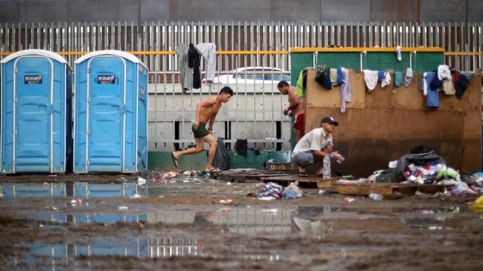 Migrants shower in front of the border wall with the United States in Tijuana on 28 November, 2018