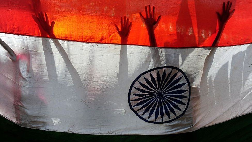 Indian schoolchildren are silhouetted against a national flag as they participate in Independence Day celebrations in Chennai on August 15, 2016.