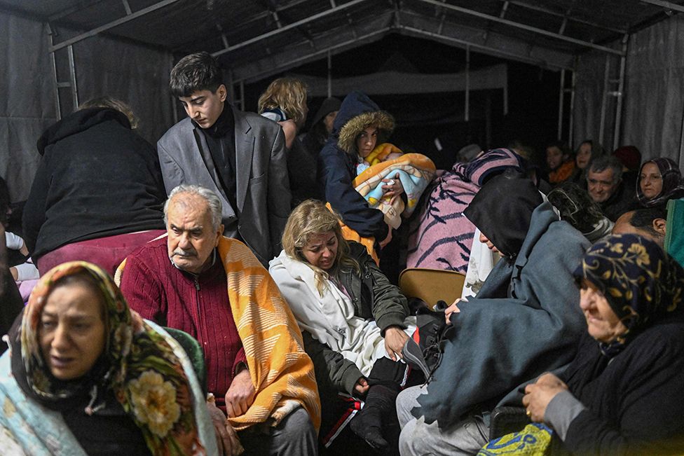 Earthquake survivors sit sheltering in a tent in Hatay, Turkey. 7 February 2023.