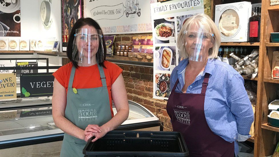Employees at a Cook Food retail store wearing visors