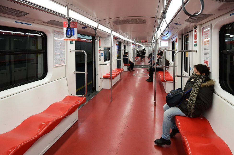 A few passengers sit in an underground train carriage