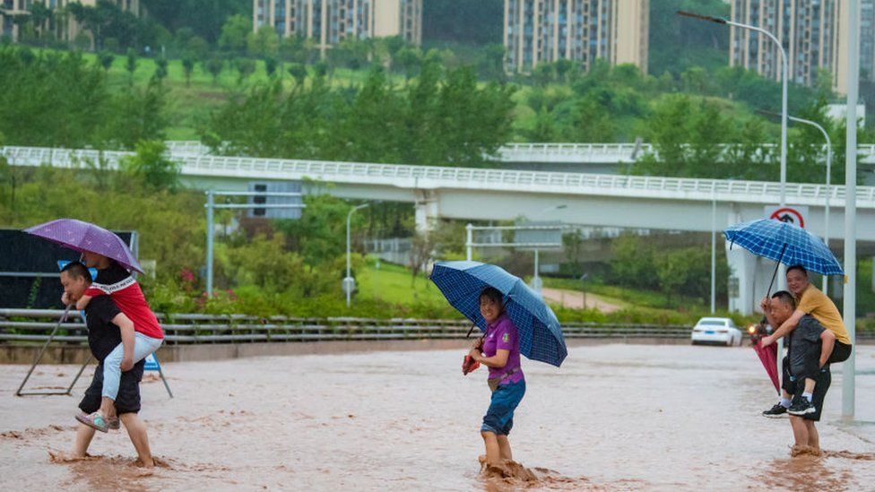 Citizen carry people to wade through floodwater after torrential rains trigger floods and landslides at Wanzhou district on July 14, 2023 in Chongqing, China.