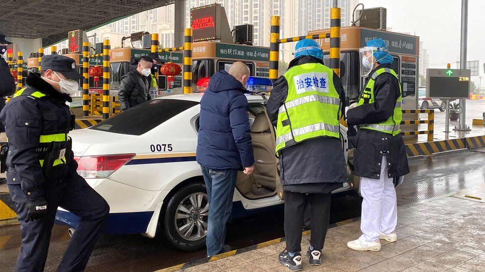 Police inspect a car at a toll station outside Wuhan, China