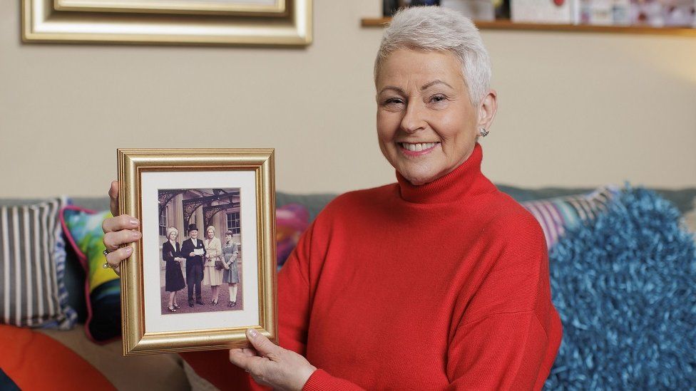 Broadcaster Pamela Ballantine, who becomes an MBE, with a photo of her family at Buckingham Palace