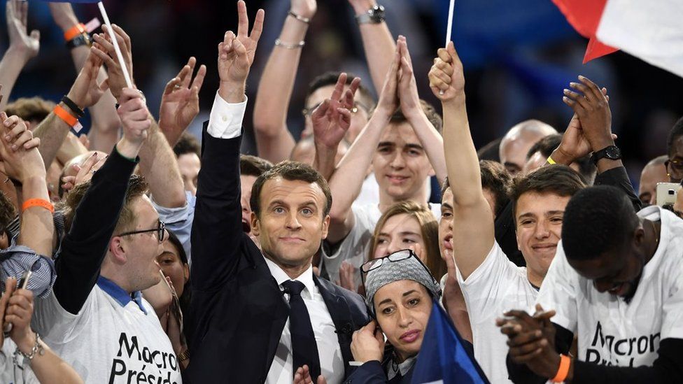 Presidential election candidate for the En Marche ! movement Emmanuel Macron flashes the "V for victory" sign surrounded with his supporters after delivering a speech during a campaign meeting on April 17, 2017