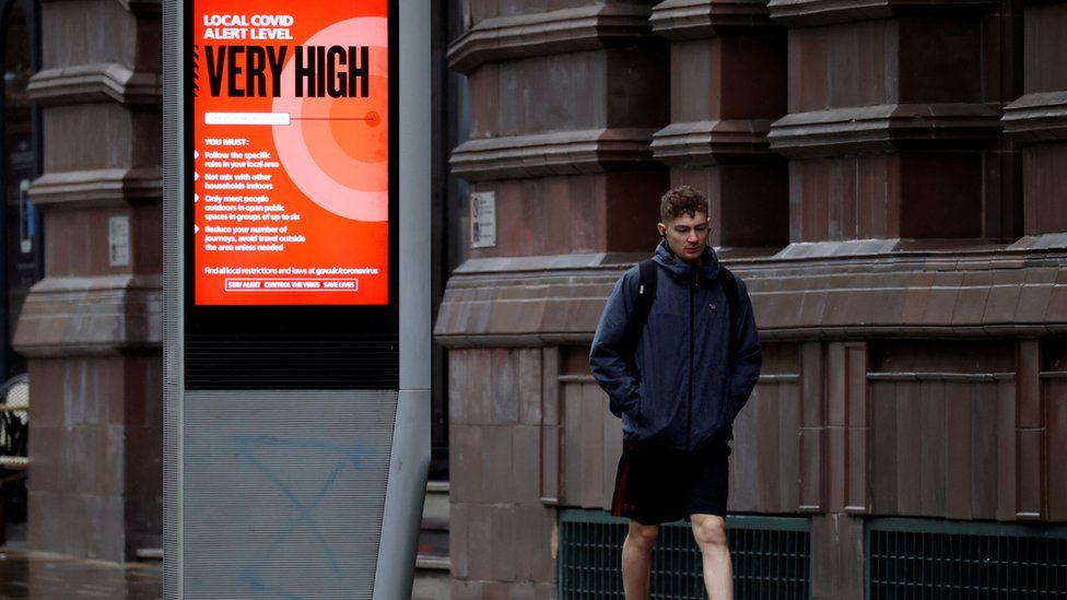 A man walks past a sign about COVID-19 measures, amid the outbreak of the coronavirus disease (COVID-19), in Manchester