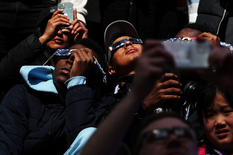 People assemble to view a partial solar eclipse, where the moon will partially blot out the sun, at Times Square in New York City, U.S. April 8, 2024. REUTERS/Shannon Stapleton