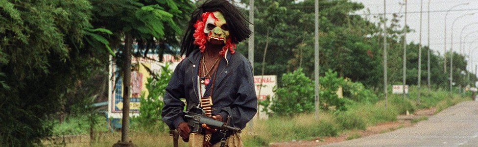 A masked fighter in Liberia's civil war
