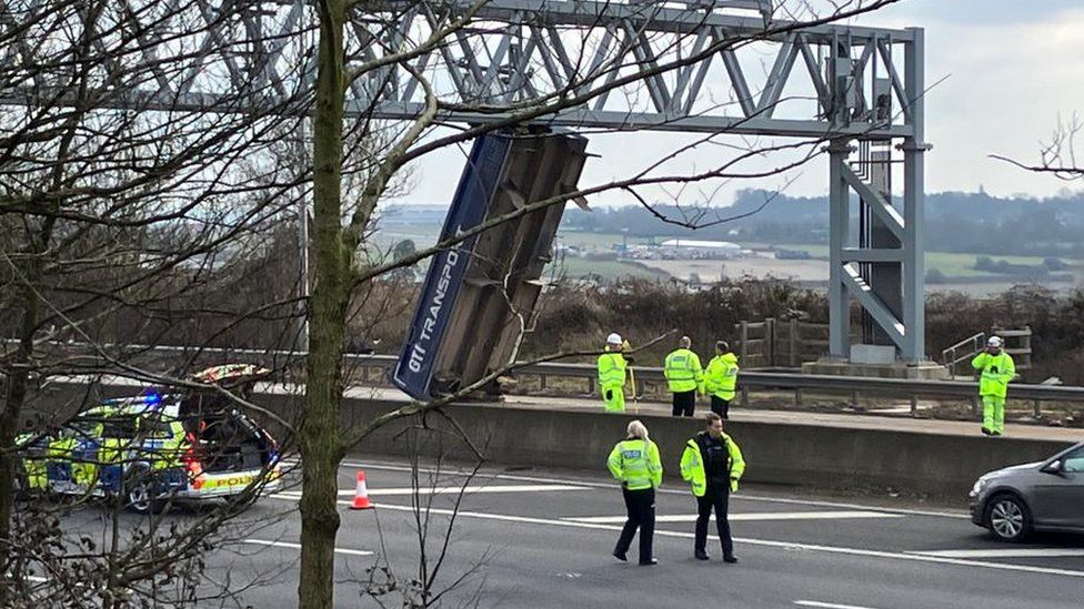 Police attending a crash on the M5. A tipper is balanced against the gantry.