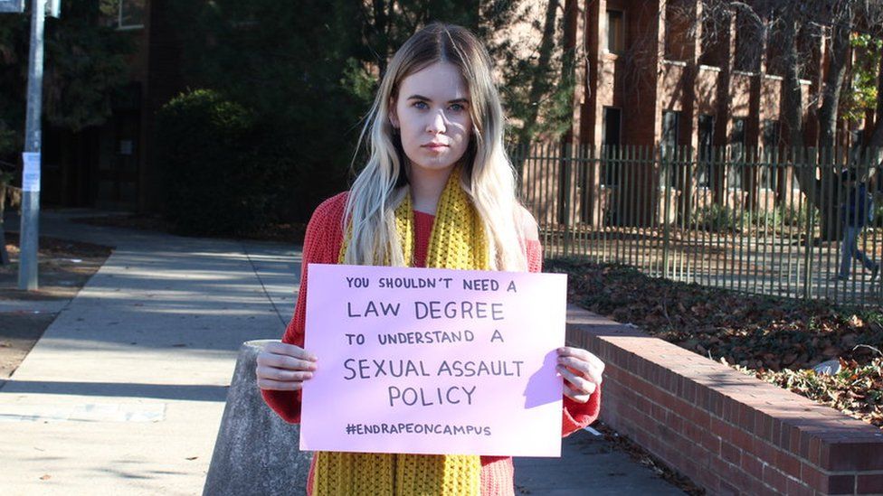 Участник акции протеста против изнасилований в университетском городке в Австралии держит плакат с надписью: «Вам не нужно иметь юридическое образование, чтобы понимать политику сексуального насилия».