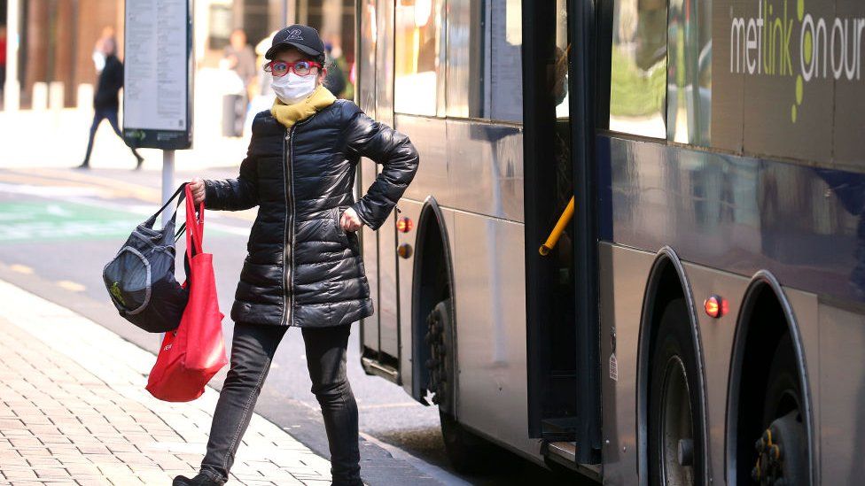 A woman wearing a face mask disembarks a public bus after a move to COVID-19 Alert Level 1 on September 22