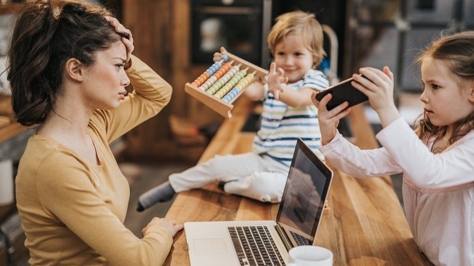 woman on laptop with two children