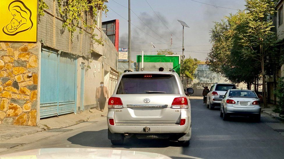 Vehicles move along a road against the backdrop of smoke rising from the site of blast in Kabul on November 2, 2021.