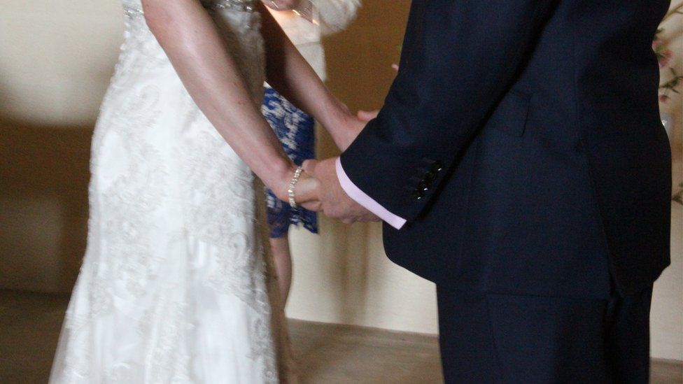 Unidentified couple holding hands at wedding