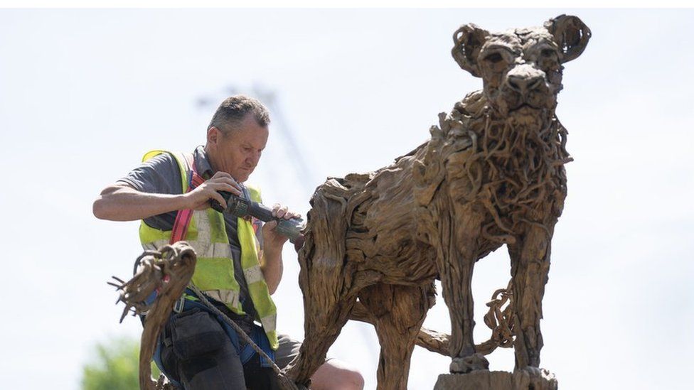 A man in a fluorescent jacket working on a garden sculpture ahead of the show