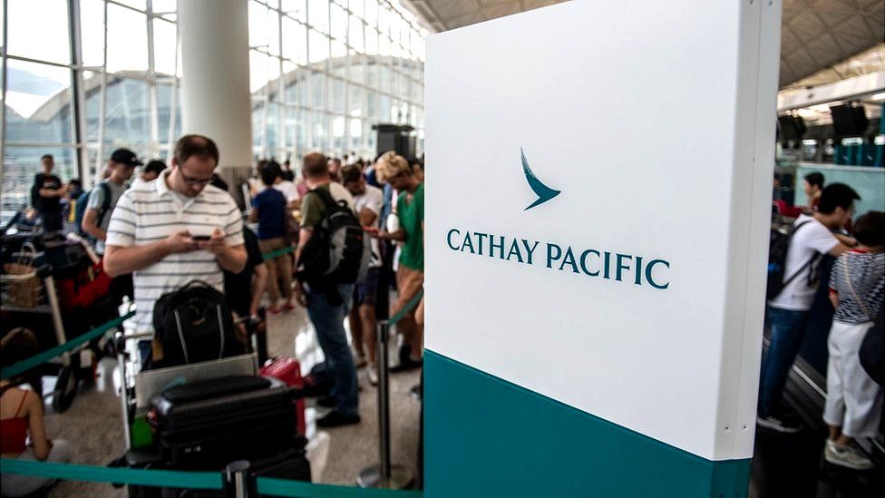 A Cathay Pacific logo (R) is seen next to a Traveler (L) in Hong Kong International Airport in Hong Kong on August 13,