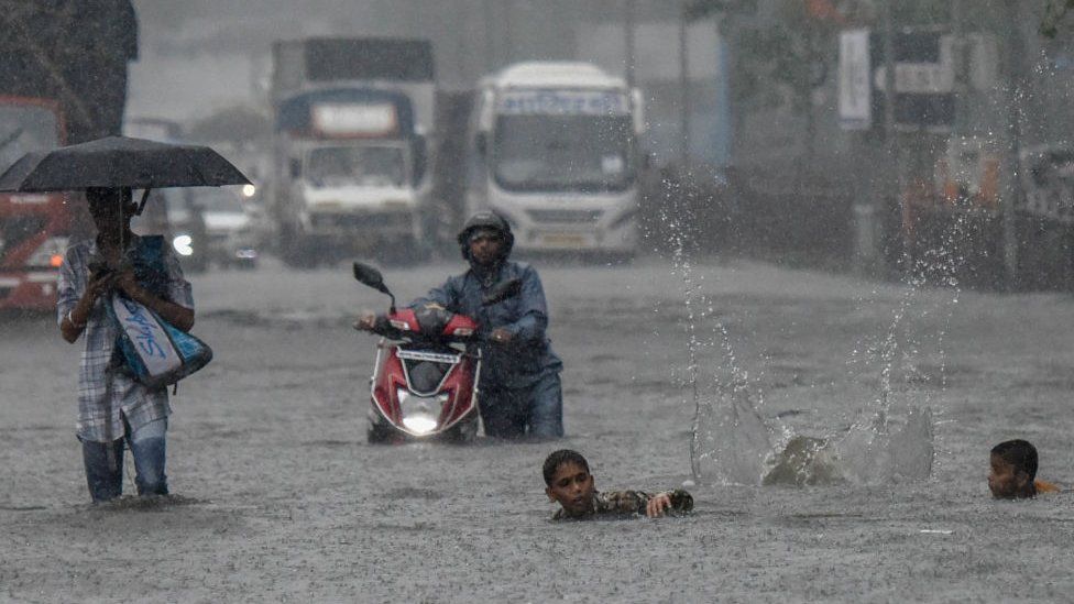 A man pushes a motorbike on a flooded street after heavy rain showers at Santacruz Chembur Link Road, on July 2, 2019 in Mumbai, India.
