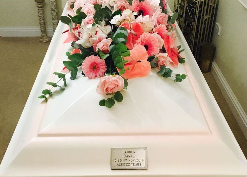 Lauren Danks white coffin with pink floral arrangement on top