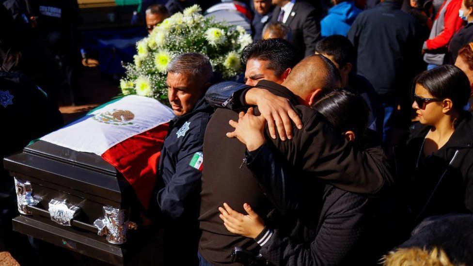 Люди обнимаются, отдавая дань уважения тюремным охранникам, убитым во время бунта в тюрьме в Сьюдад-Хуаресе, Мексика