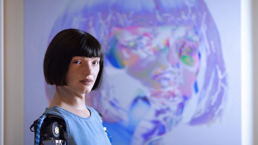 Ai-Da stands in front of one of 'her' artworks.