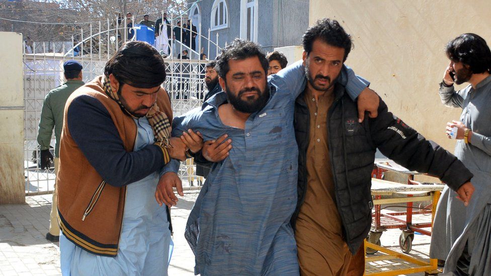 A bomb blast victim (2L) is helped to walk into a hospital in Quetta on February 7, 2024.