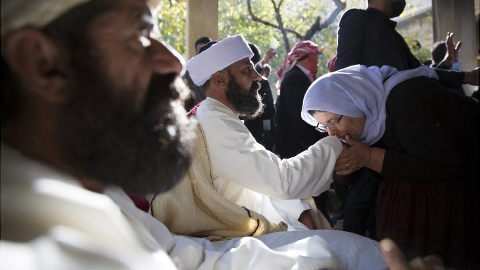 A woman kisses the hand of the new Baba Sheikh