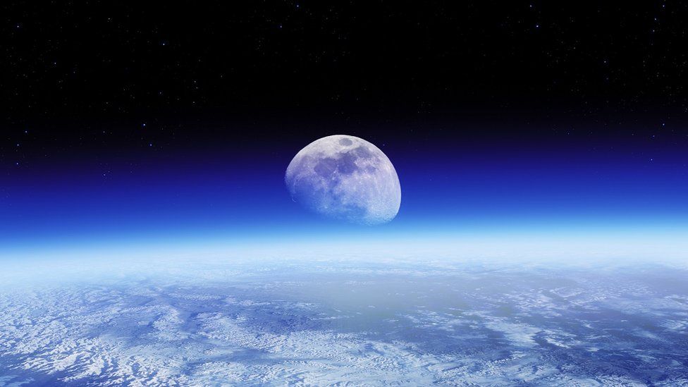 The moon, rising over the earth's surface