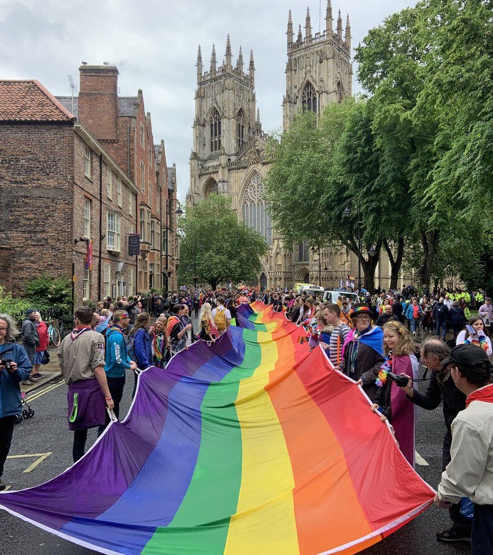 People holding a very long flag as they parade through a York street