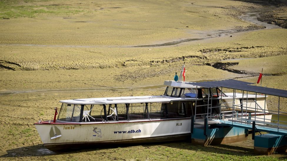 A boat trapped in mud on the dried-out shore of Lac des Brenets - part of the Doubs river, a natural border between France and Switzerland, 17 Aug 22