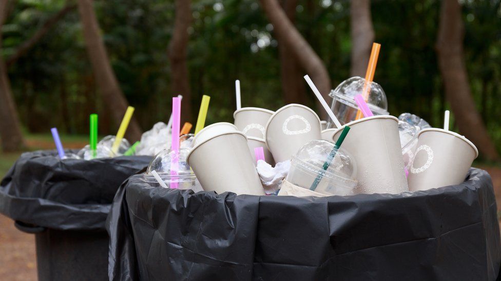 Straws and cups in an overflowing bin