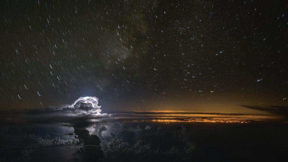 Horizonte rojizo y nubes blancas y negras vistas desde la cabina cubierta por gotas de agua