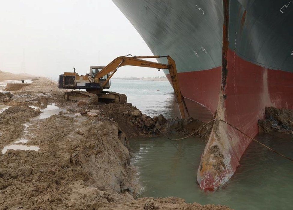 A digger attempts to remove earth around the bow of the Ever Given, which is blocking the Suez Canal, Egypt (25 March 2021)