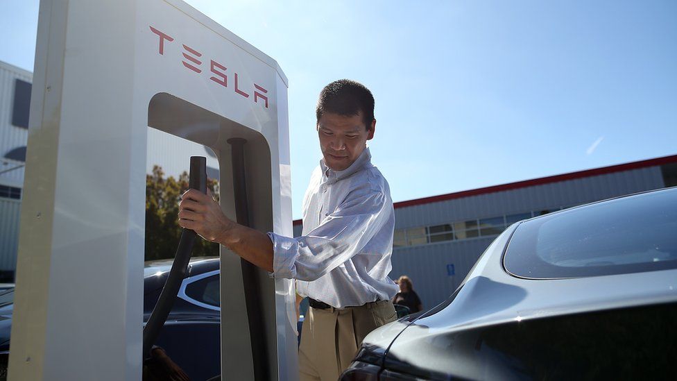 A man prepares to plug into a Tesla charging station in Fremont, California