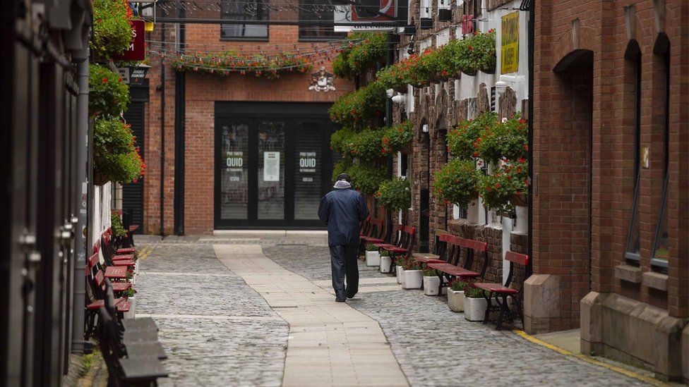 A man walks down an eerily quiet Commercial court in Belfast city centre
