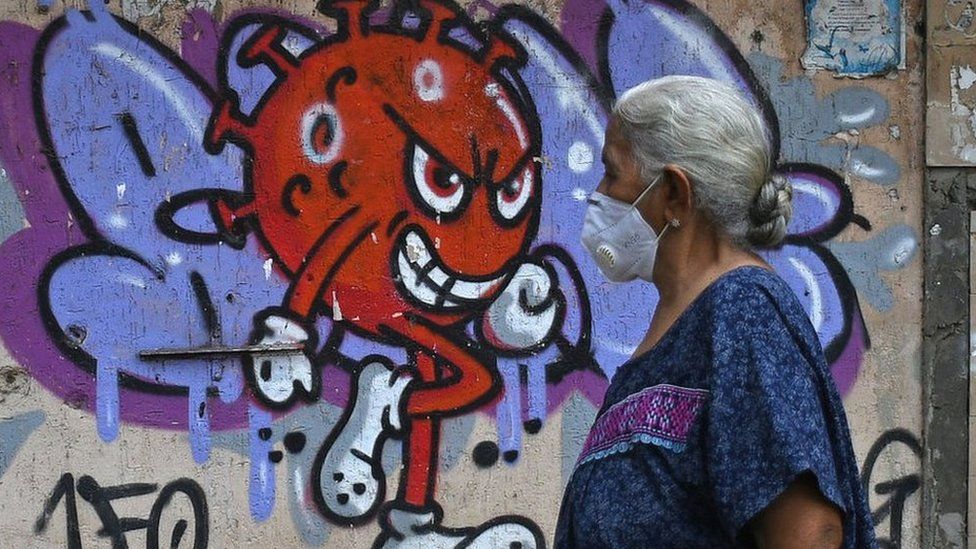 A woman wearing a protective mask walks past a painted graffiti to raise awareness of the coronavirus disease in Mumbai.  12 Oct 2021