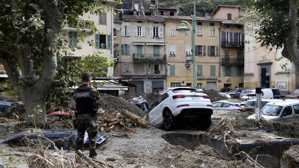 A gendarme stands amongst debris including vehicles in Breil-sur-Roya, south-eastern France