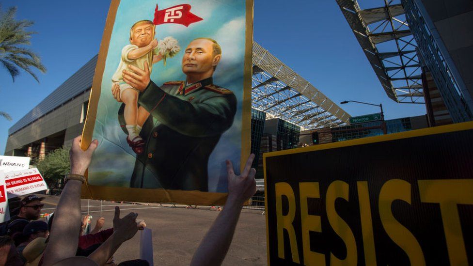плакат - путин держит трампа на руках
