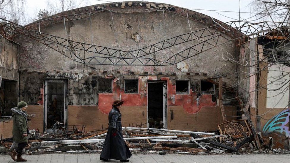 Residents walk past destroyed buildings in the town of Sviatohirsk, Donetsk