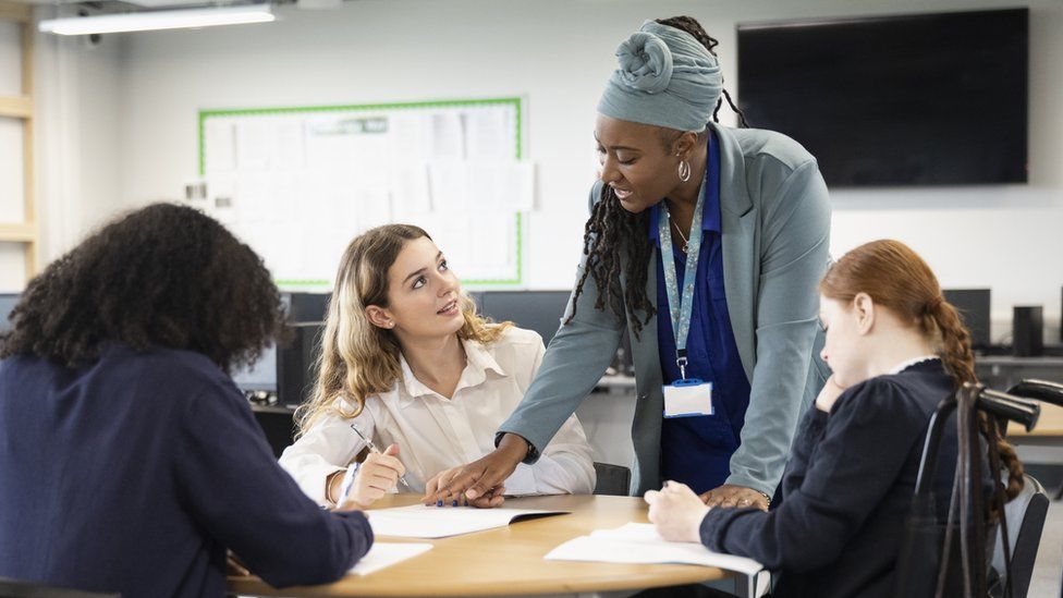 Female students working on assignment with help from black teacher