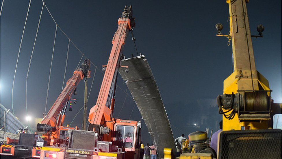 Рабочие снимают часть подвесного моста (C) после обрушения конструкции через реку Маччху в Морби, примерно в 220 км от Ахмедабада, ранним утром 31 октября 2022 г.