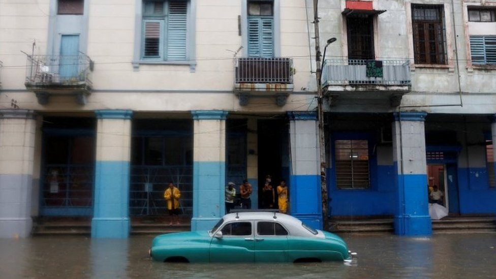 A vintage car breaks down in floodwaters on a Havana street