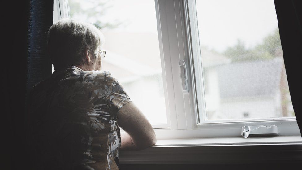 Elderly woman looking out of window